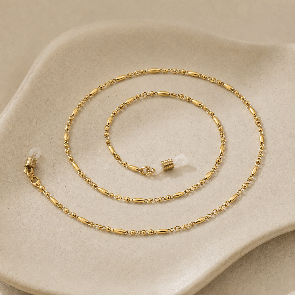 Berthille, chaîne de lunettes à perles dorées posée à plat, JACQUAND