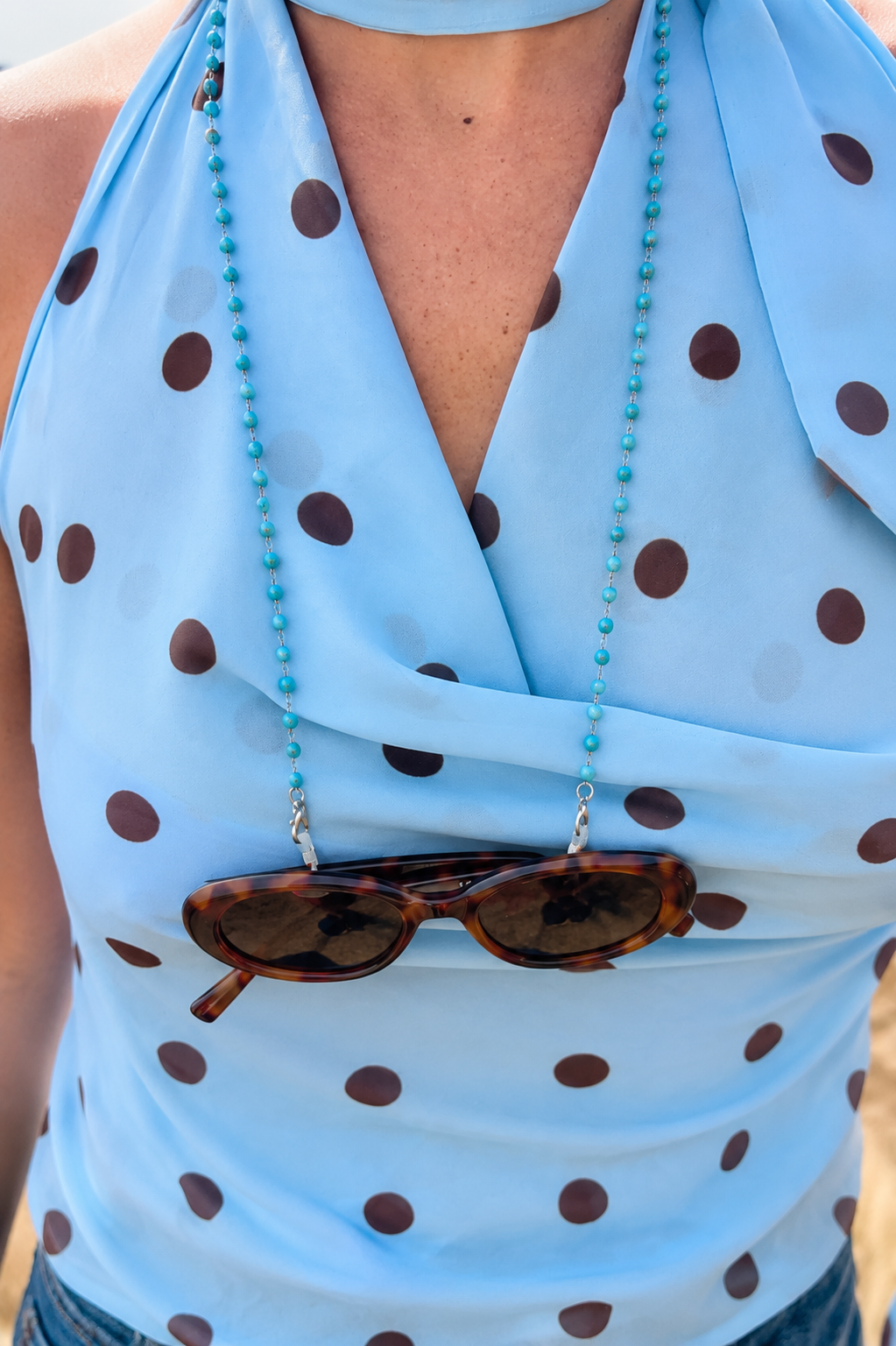 Marguerite portée en chaîne de lunettes sur un haut bleu à pois, JACQUAND